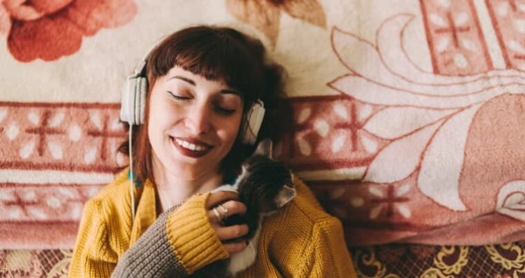 Gen Z und mentale Gesundheit: Frau hört Musik und spielt mit der Katze