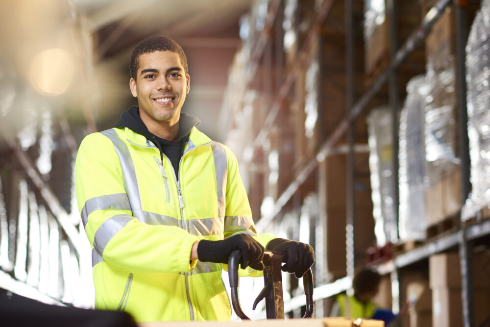 a male warehouse worker smiles to camera .